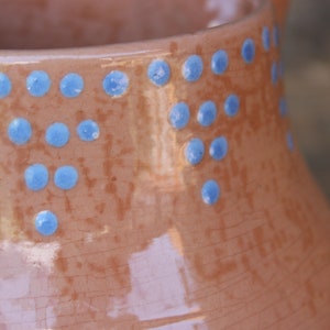 May include: A brown ceramic jug with a speckled glaze and a decorative pattern of blue dots around the top.