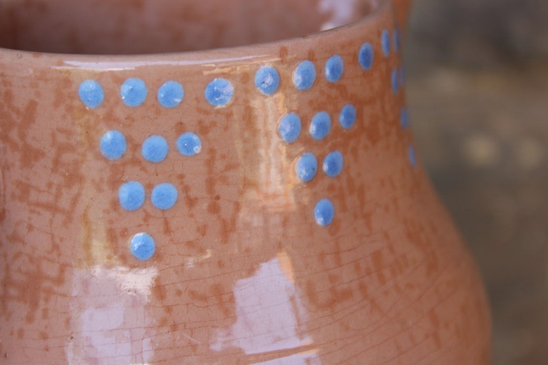 May include: A brown ceramic jug with a speckled glaze and a decorative pattern of blue dots around the top.