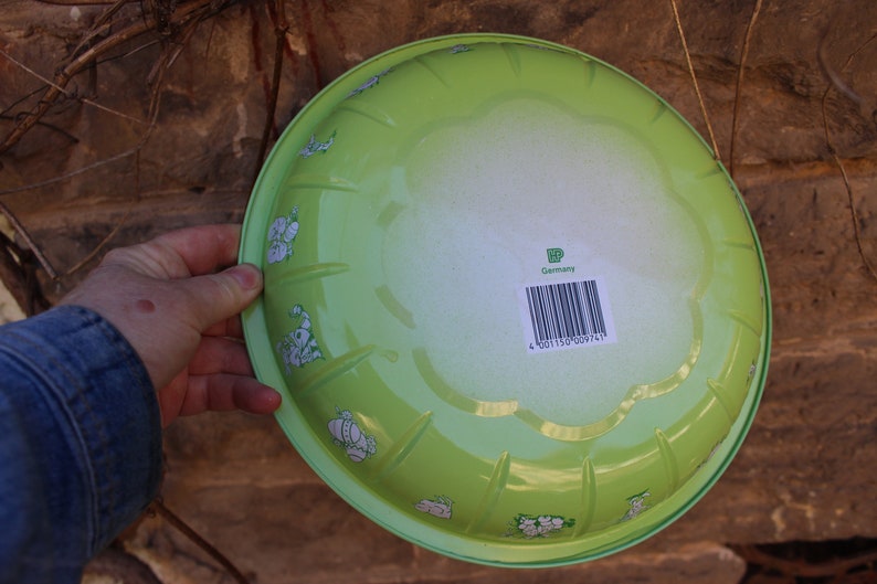 May include: A green enamelware bowl with a white floral design and a barcode label that reads "Germany".