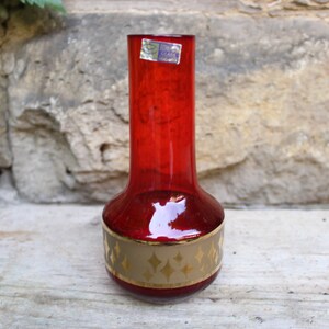 Könnte beinhalten: Eine rote Glasvase mit einem goldenen Band und geometrischem Design. Die Vase ist etwa 25 cm hoch.