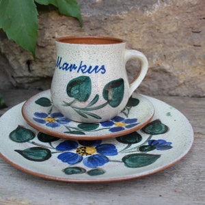 Könnte beinhalten: Ein weißes Keramik-Tee-Set mit blauem und grünem Blumendesign. Die Teetasse trägt die Aufschrift "Markus".