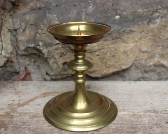 May include: A gold metal candle holder with a round base and a single candle holder on top.