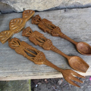 May include: Set of three wooden spoons with intricate carvings. The spoons are brown and have a natural wood finish. The spoons are arranged on a wooden surface.
