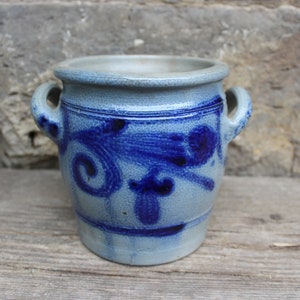Könnte beinhalten: Ein kleiner, grauer Steinzeugtopf mit blauen Blumendesigns und zwei Henkeln.