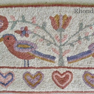 May include: A hand-stitched rug with a floral design featuring two birds, a tree, and hearts. The rug is made with a variety of colors, including red, pink, blue, and green. The text "Rhonda Thomas (c)" is in the upper right corner of the rug.