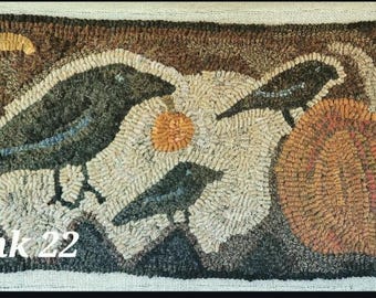 May include: Hand-hooked rug featuring three crows, a pumpkin, and a stylized sun. The rug is primarily brown, beige, and orange, with the text "kank 22" in the lower left corner. The design evokes a rustic, autumnal theme.