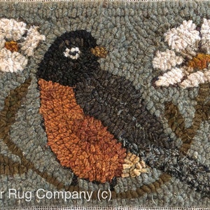 May include: A hand-stitched rug depicting a robin perched on a branch with two white flowers on either side. The background is a muted green color. The rug is signed "Star Rug Company (c)".