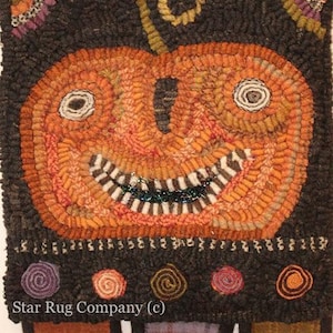 May include: A hand-stitched wool rug depicting a smiling orange pumpkin with a black background and a border of colorful swirls. The rug has a "Star Rug Company (c)" signature at the bottom.