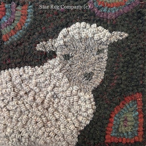 May include: A close-up of a gray and white wool rug depicting a sheep. The sheep is made of individual loops of wool and is set against a dark green background with red and blue accents.