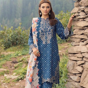 Puede incluir: Un vestido de lunares azules y blancos con bordados florales y una chal a juego. El vestido tiene manga larga y cuello redondo. El chal tiene un patrón floral con flores naranjas, rosas y blancas.