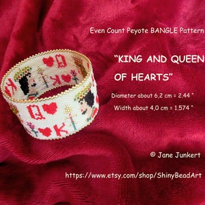 May include: A white beaded bracelet with a King and Queen of Hearts design. The bracelet is 2.44 inches in diameter and 1.574 inches wide. The bracelet is on a red fabric background.