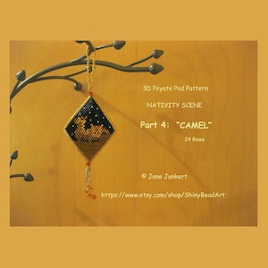 Könnte beinhalten: Ein Perlenornament, das ein Kamel in einem schwarzen und goldenen Peyote-Stichmuster darstellt. Das Ornament ist mit "3D Peyote Pod Pattern Nativity Scene Part 4: "CAMEL" 24 Rows" und "Jane Junkert https://www.etsy.com/shop/ShinyBeadArt" beschriftet.
