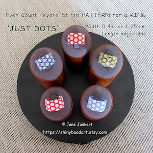 May include: Four beaded rings on display stands. The rings are made with even count peyote stitch and feature a "JUST DOTS" pattern. The rings are red and white, blue and white, green and white, and yellow and white. The rings are 0.49 inches wide or 1.25 cm wide and the length is adjustable.