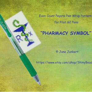 Könnte beinhalten: Ein grüner Pilot G2 Stift mit einer weißen Karte, die ein Peyote-Stichmuster eines Apotheken-Symbols zeigt. Die Karte lautet "Even Count Peyote Pen Wrap Pattern for Pilot G2 Pens" und "Pharmacy Symbol". Die Karte enthält auch den Namen der Künstlerin, Jane Junkert, und einen Link zu ihrem Etsy-Shop, ShinyBeadArt.