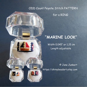 Könnte beinhalten: Ein Perlenring mit einem Segelboot-Design in den Farben Rot, Weiß, Blau, Gold und Braun. Der Ring befindet sich in einer durchsichtigen Plastikbox. Der Text "MARINE LOOK" befindet sich über der Box. Der Text "Breite 0,045" oder 1,15 cm" befindet sich unter der Box. Der Text "Länge einstellbar" befindet sich unter dem Text der Breite. Der Text "Jane Junkert" befindet sich unter dem Text der Länge. Der Text "https://shinybeadart.etsy.com" befindet sich unter dem Text von Jane Junkert.