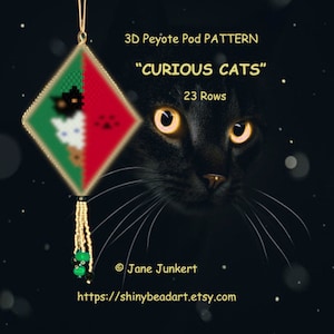 Peut inclure: Un motif de broderie en peyote 3D intitulé "Curious Cats" avec 23 rangées. Le motif est en forme de losange avec un fond vert et rouge et un motif de chat noir et blanc. Le motif est suspendu à un cordon doré avec des perles vertes au bas.