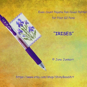 May include: A purple Pilot G2 07 pen is lying on top of a white and purple beaded pen cover pattern with the text "IRISES" and "Even Count Peyote Pen Cover Pattern for Pilot G2 Pens".