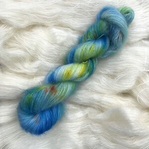 May include: A skein of hand-dyed yarn in shades of blue, green, and yellow. The yarn is soft and fluffy, and it would be perfect for knitting or crocheting a scarf, hat, or sweater.