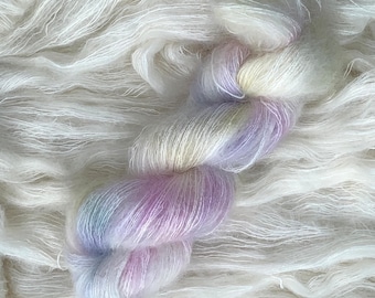 May include: A skein of soft, white yarn with a colorful strand of yarn in shades of purple, blue, and yellow.