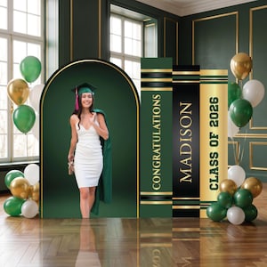 May include: A woman in a white dress and graduation cap poses in front of a green backdrop with gold accents. The backdrop features the words "Congratulations," "Madison," and "Class of 2026." Balloons in gold, green, and white are also present.