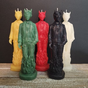 Può includere: Cinque candele decorative a forma di figure con corna e fiamme ai loro piedi. Le candele sono gialle, verdi, rosse, nere e bianche.