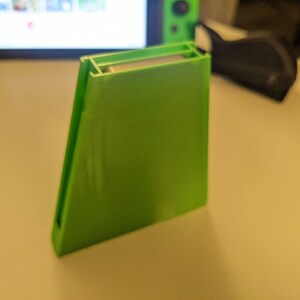 May include: A bright green plastic case with a slightly textured surface. The case is empty and has a rectangular shape.