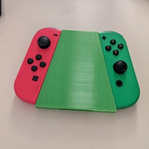 May include: A green and red Nintendo Switch console with the Joy-Con controllers attached. The console is in a closed position.