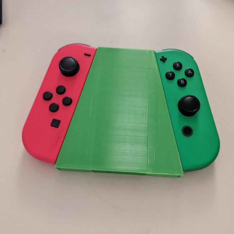 May include: A green and red Nintendo Switch console with the Joy-Con controllers attached. The console is in a closed position.