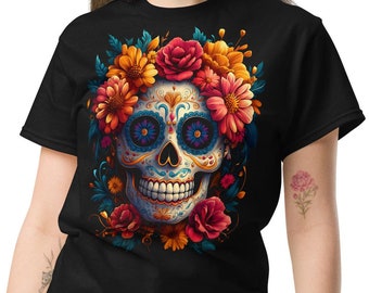 May include: Black t-shirt featuring a colorful sugar skull design with floral accents. The skull has intricate patterns and is surrounded by red, orange, and yellow flowers. The design is centered on the front of the shirt.