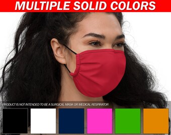 May include: A red face mask with black elastic ear loops. The mask is made of a soft, breathable fabric and has multiple pleats. The mask is shown being worn by a person with long dark hair. The text "PRODUCT IS NOT INTENDED TO BE A SURGICAL MASK OR MEDICAL RESPIRATOR" is displayed below the image.  The image also shows a variety of colors the mask is available in: black, white, navy blue, pink, green, and orange.