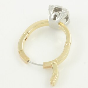 May include: A pair of gold hoop earrings with a hinged closure. The earrings are made of two-toned metal, with a gold band and a silver top. The top of the earring features a diamond-shaped stone.