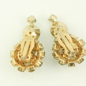 Peut inclure: Une paire de boucles d'oreilles clips en or avec un groupe de strass vert clair.