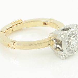 May include: A gold and white ring with a square-shaped diamond surrounded by smaller diamonds.