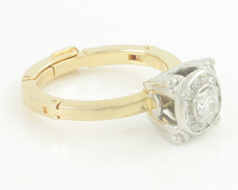 May include: A gold and white ring with a square-shaped diamond surrounded by smaller diamonds.