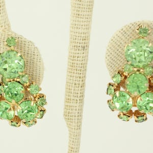 Peut inclure: Une paire de boucles d'oreilles pendantes avec un groupe de strass vert clair sertis dans un m&eacute;tal dor&eacute;.