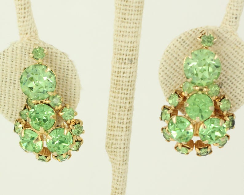 Peut inclure: Une paire de boucles d'oreilles pendantes avec un groupe de strass vert clair sertis dans un m&eacute;tal dor&eacute;.