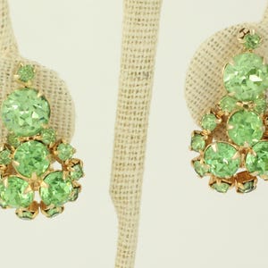 Peut inclure: Une paire de boucles d'oreilles pendantes avec un groupe de strass vert clair sertis dans un m&eacute;tal dor&eacute;.