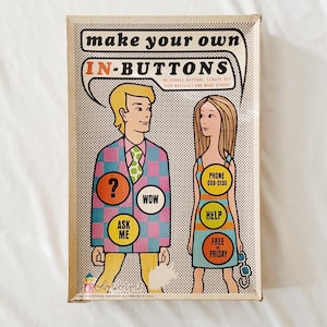 May include: A vintage box game called "Make Your Own In-Buttons." The box features a cartoon illustration of two people with colorful buttons that say "Ask Me," "Wow," "Help," "Free Friday," and "Phone 089-5130."