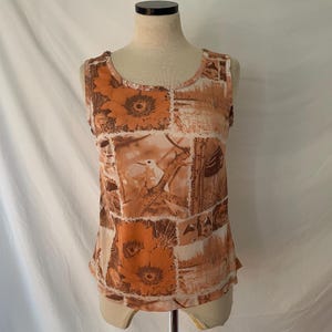 May include: A sleeveless tank top with a brown and white floral print. The print features sunflowers, birds, and other botanical elements.