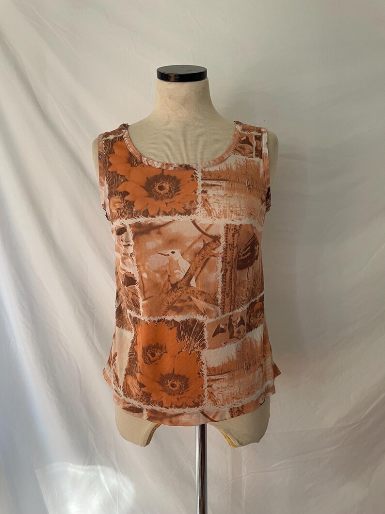 May include: A sleeveless tank top with a brown and white floral print. The print features sunflowers, birds, and other botanical elements.