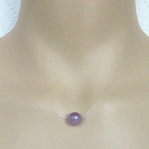 Puede incluir: Un collar delicado con un solo colgante de piedra preciosa redonda de color púrpura claro.