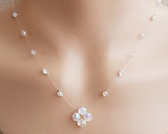 May include: A delicate, clear necklace with a small, iridescent crystal pendant. The necklace is made of thin, clear string and features small, clear crystals spaced evenly along the length.