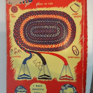 May include: Vintage hobby kit box with a red background and yellow center. The box features illustrations of items like hot pads, slippers, and hand bags. Text includes "NEW!" and "HOBBY KIT". The box is designed to make beautiful gifts.