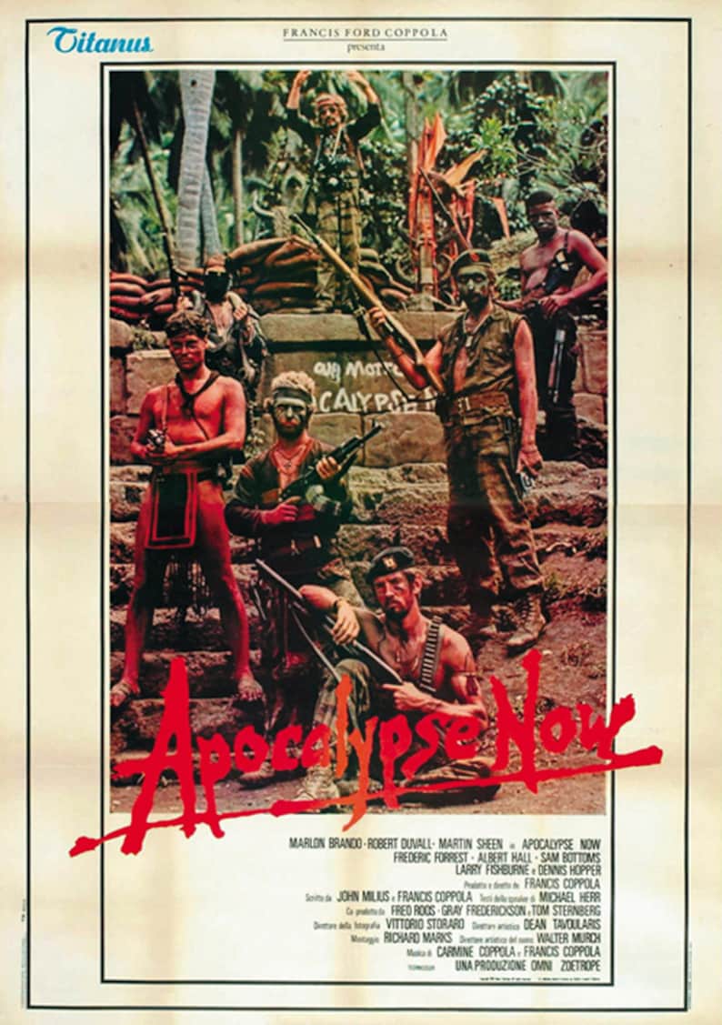 Op de afbeelding: Een vintage filmposter voor de film Apocalypse Now, met een groep soldaten in een jungle-omgeving. De poster is in rood, wit en zwart met de titel "Apocalypse Now" in grote rode letters. De poster toont ook de namen van de acteurs, waaronder Marlon Brando, Robert Duvall en Martin Sheen.