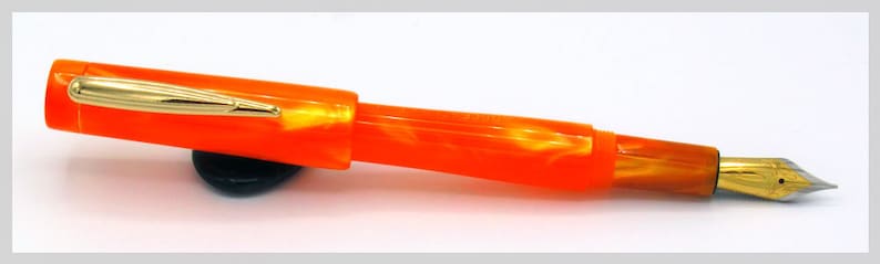 May include: Orange and gold fountain pen with a marbled orange body and a gold nib.