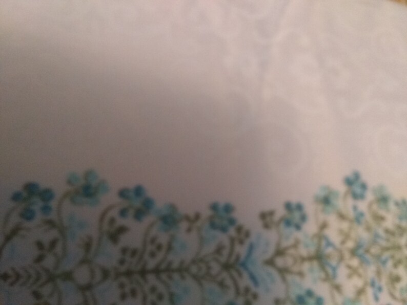 Columns of tiny blue flowers between white curling design on cream cotton polyester blend