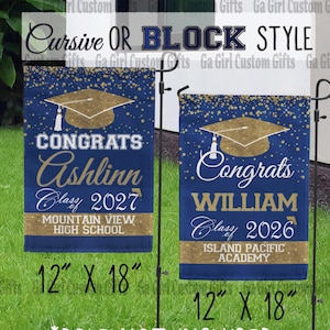 May include: Two graduation garden flags, each 12" x 18", with navy blue and gold designs. One says "Congrats Ashlinn Class 2027" and the other says "Congrats William Class 2026". The flags have a gold graduation cap design.
