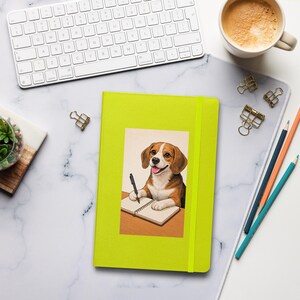 May include: A bright green notebook with a beagle illustration writing in a notebook. The notebook has a matching elastic band. A white keyboard, coffee cup, and pencils are also on the white marble surface.