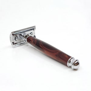 May include: A silver safety razor with a brown marbled handle.