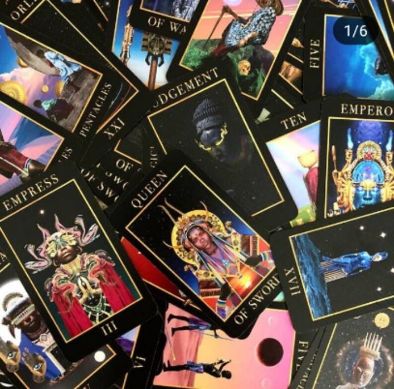 以下が含まれることがあります： 黒色の背景と金色のアクセントが施されたタロットカードのスプレッドのクローズアップ。カードには人々やシンボルのイラストが描かれています。カードには「女帝」、「ソードの女王」、「審判」などの名前が書かれています。